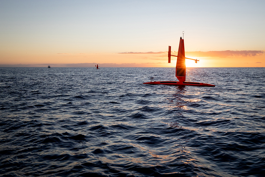 A Saildrone unmanned ocean vehicle at sunset on the ocean