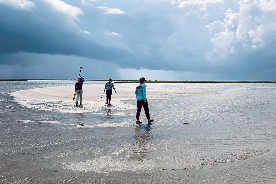 Three people walking on a beach