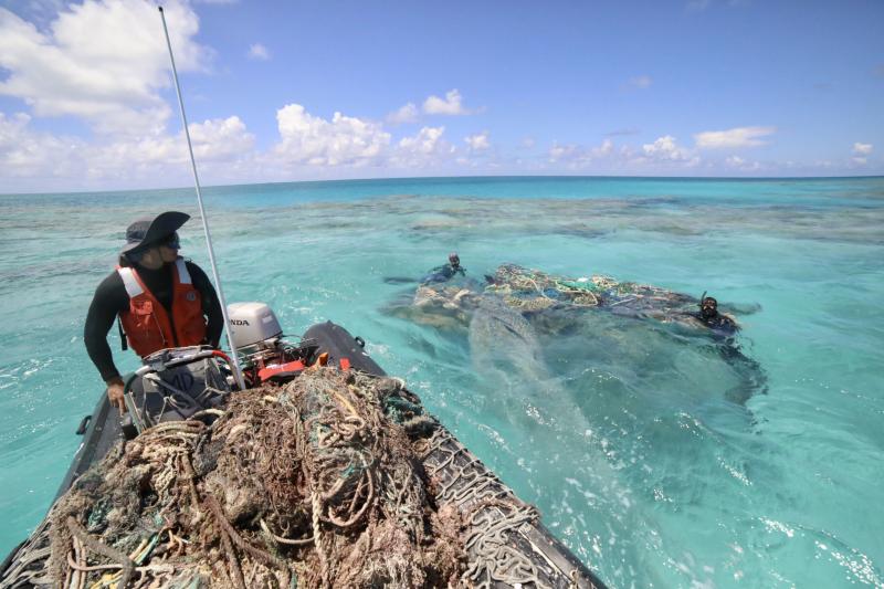 NOAA Coxswain William Reich and divers Rebecca Weible and Alika Garcia survey and find a large derelict fishing net at Kamokukamohoaliʻi (Maro Reef). Photo credit: NOAA Fisheries/James Morioka.