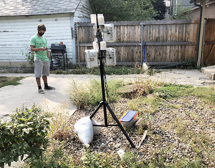 Photo of engineer testing air monitor device in a residential yard