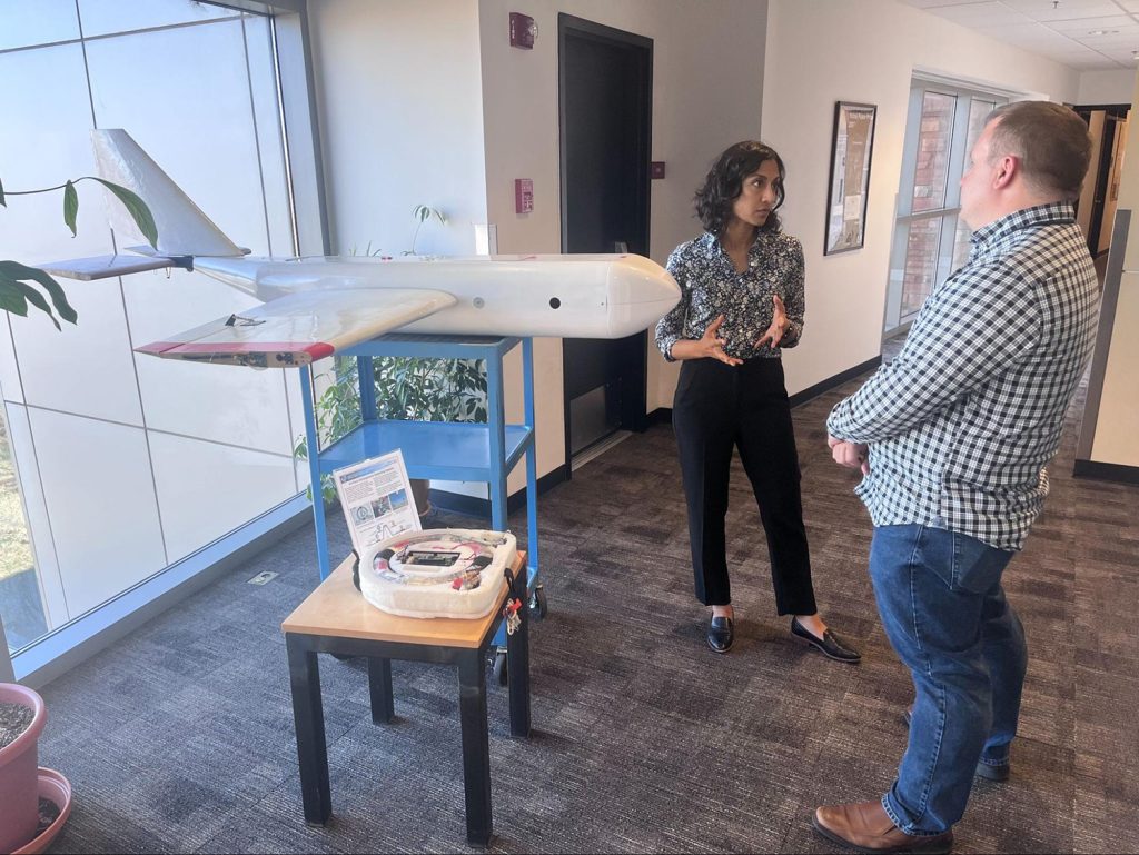 Two people stand talking near a drone.