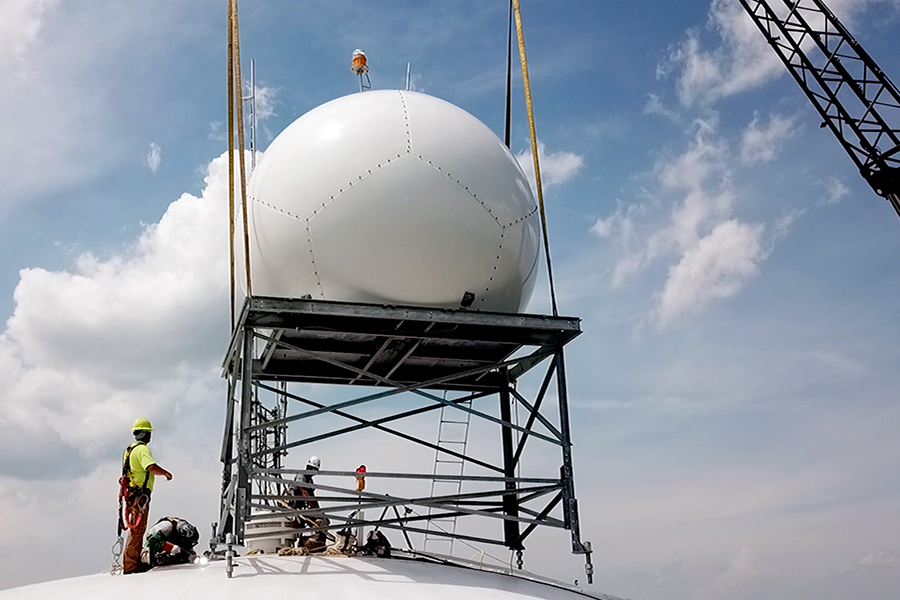 A person stands near a radar dome