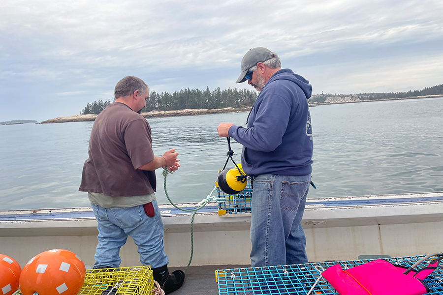 Two people on a boat examine a fishing buoy
