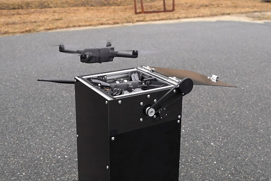 A drone hovers above a landing pedestal